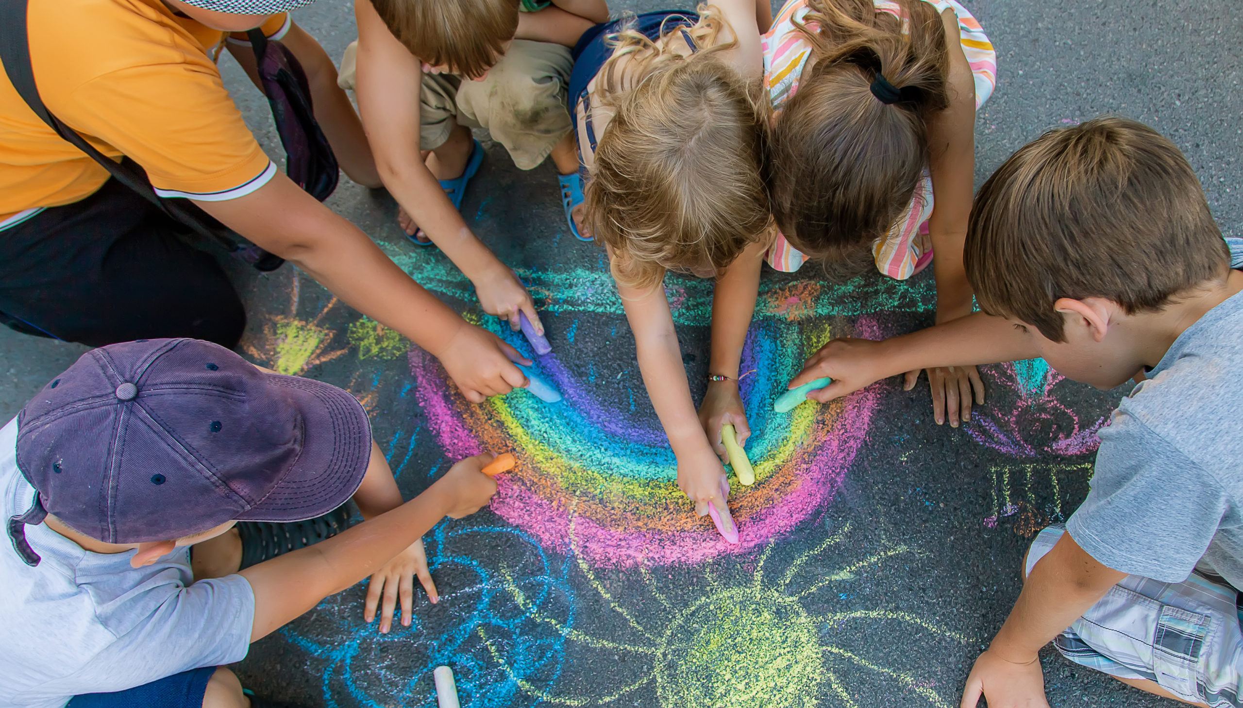 Children paint a rainbow on the asphalt. Selective focus. Kids.